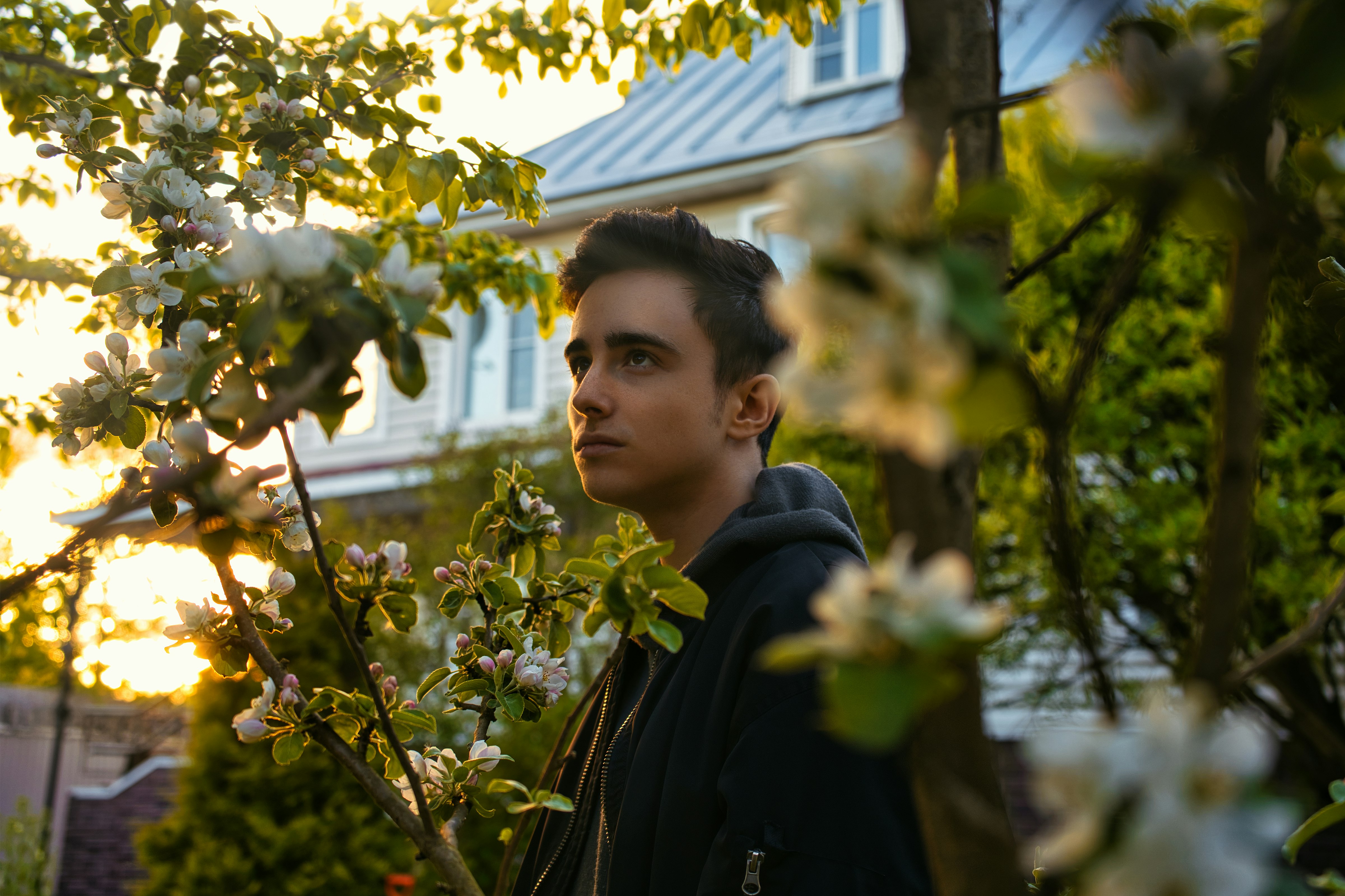 man in black jacket standing beside white flowers during daytime